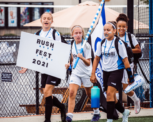 girls walking into rush fest with sign